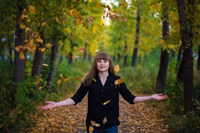 Portrait of young woman standing in park during autumn