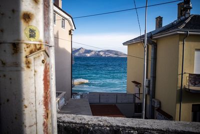 Buildings by sea against sky