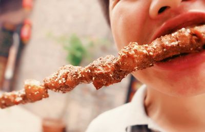 Midsection of man eating meat skewer