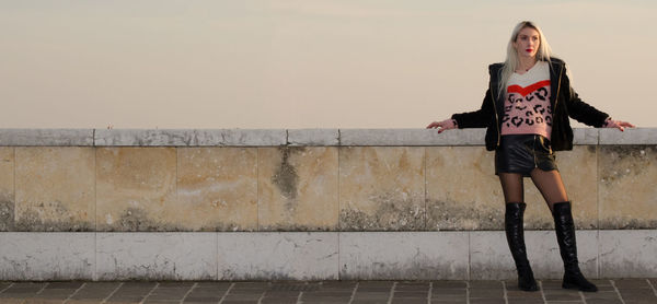 Full length of woman standing against wall