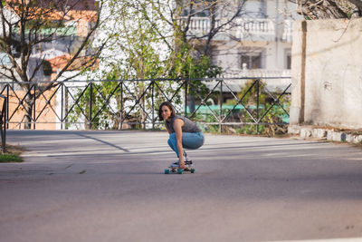 Full length of woman skateboarding on road