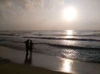 High angle view of couple holding hands while standing on beach by sea