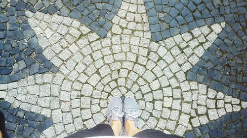 Low section of woman standing on cobblestone