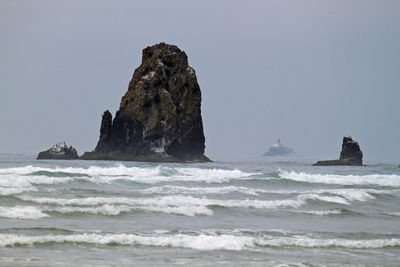 Rock formation in sea against clear sky