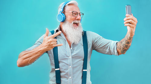 Low angle view of man using smart phone against blue background