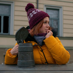 Portrait of woman wearing hat against house