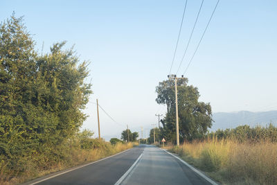 Road by trees against sky