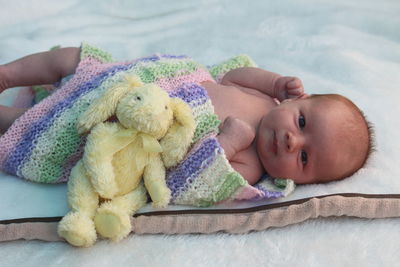 Portrait of baby with toy relaxing on bed