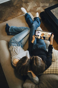 High angle view of girls video conferencing with friends through laptop at home