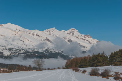 A picturesque landscape view of the snowcapped french alps mountains with a hiking path in the snow