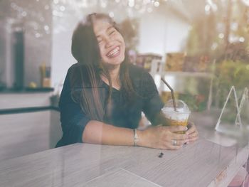 Happy woman with drink sitting on table at restaurant