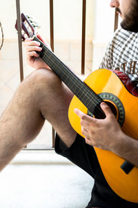 Midsection of man playing guitar