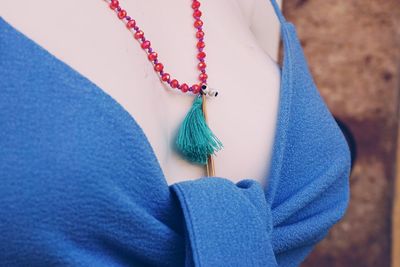 Midsection of woman hanging against blue wall