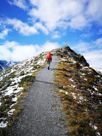 Rear view of woman walking on mountain against sky