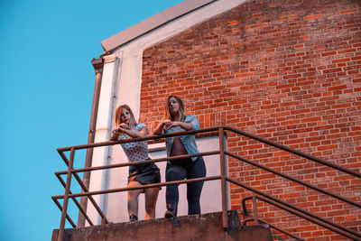 Low angle view of female friends standing in balcony