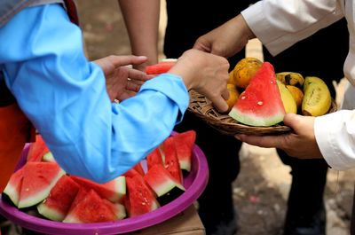 Midsection of people holding fruits
