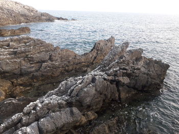 Rock formation on sea shore against sky