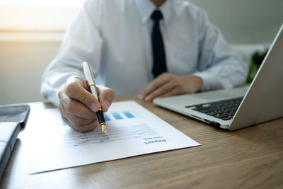 Midsection of man using mobile phone on table