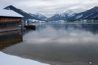 Scenic view of frozen lake by snowcapped mountains against sky