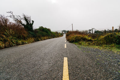 Diminishing perspective of empty road amidst plants against sky