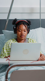 Female patient using laptop on bed