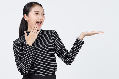 Portrait of smiling young woman standing against white background