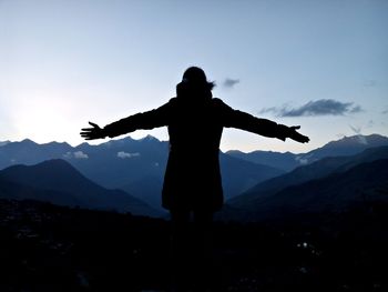 Rear view of person with arms outstretched standing against mountains