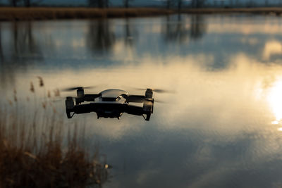 Small modern drone hovering taking picture of sunset.