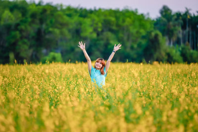 Rear view of woman with arms outstretched on grassy field