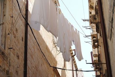 Low angle view of clothesline hanging against sky