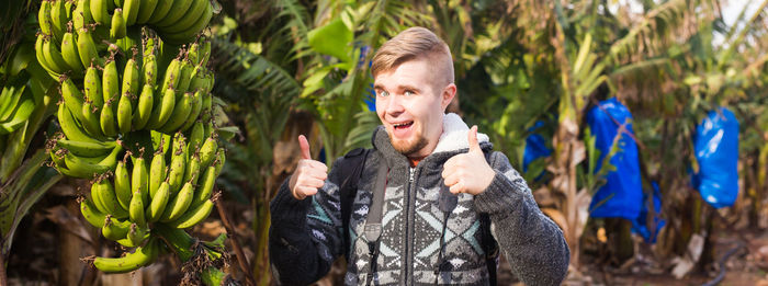 Young man standing against plants