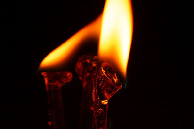 Close-up of burning drinking straw against black background