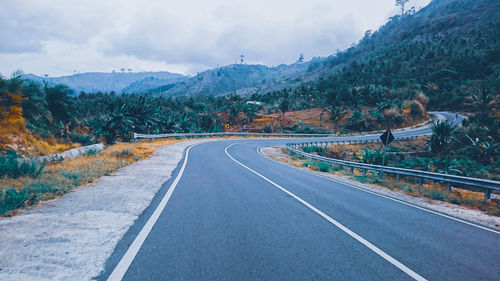 Empty road by mountains against sky