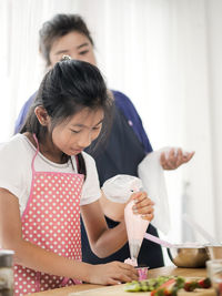 Young woman holding ice cream standing on table