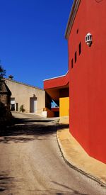 Street amidst buildings against clear blue sky