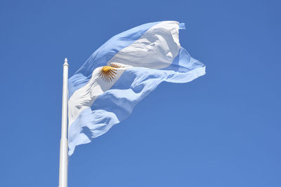 Argentine flag flying on a flagpole against a blue sky on a sunny day. patriotic symbol of argentina