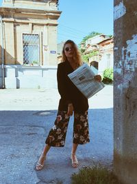 Full length of young woman standing against building in city