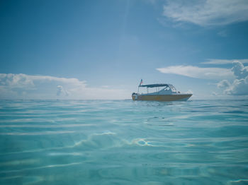 Low angle boat mooring on a turquoise crystal clear water against blue skies.