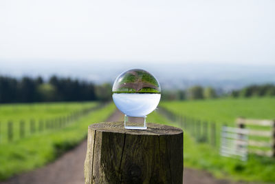 Light bulb on wooden post on field against sky