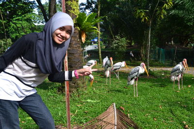 Portrait of smiling young woman with birds in park