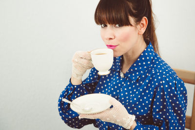 Portrait of young woman holding coffee cup over white background