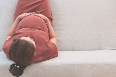 Directly above shot of pregnant woman sitting on sofa at home