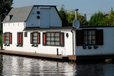 House by river against buildings in city