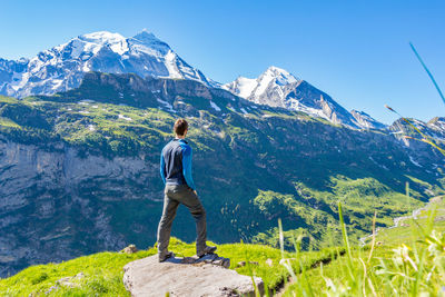 Rear view of man standing on mountain against clear sky