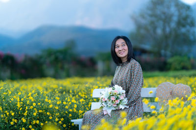 Woman standing on yellow flowering plants on field