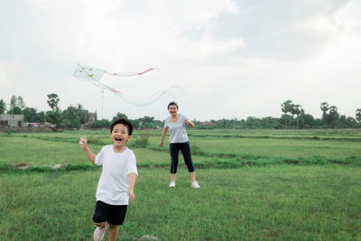 Full length of friends standing on field against sky