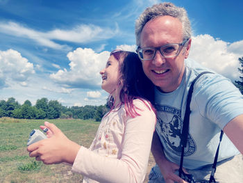 Portrait of young man photographing against sky