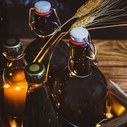 Bottles with cold, homemade, light and dark, unfiltered beer with ears of wheat and twinkling lights