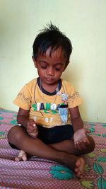 Cute boy sitting on bed at home