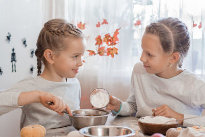 Treats and preparations for the celebration of halloween. two girls prepare halloween cookies 